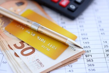 Credit card and pen with euro currency money bills banknotes on calculations document background. Business, financial operations and accounting in European Union