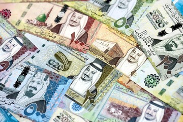 Saudi Arabia riyal money bills banknotes lies in big pile on table close up. Concept of finances and business in Saudi Arabia