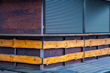 Wooden structure with natural planks and metal shutters forming the exterior of a closed booth in an urban space