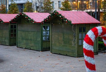 Christmas market wooden stalls decorated with festive garlands and ornaments, arranged in the city...
