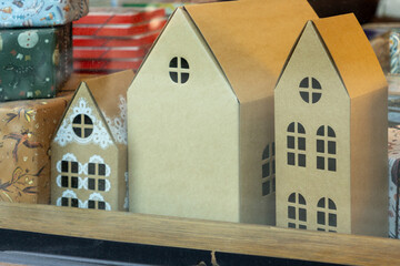 showcase with Christmas gifts and houses. The houses are made of cardboard, and the gifts are wrapped in green paper. The scene is festive and cheerful. Celebrating Christmas and New Year.