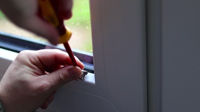 Close up of a caucasian man installing white blinds on kitchen window in a house, modern plisses shades from sunlight 