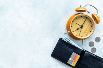 Black wallet with money cash bank card and alarm clock. Time to pay taxes or credit concept