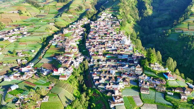 Stunning aerial footage of a mountain valley village with agricultural terraces, showing rural life and scenic nature from above. Nepal Van Java Village, Mount Sumbing, Indonesia.