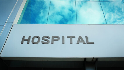Hospital sign displayed on a modern building with bright cloud reflections across large glass windows, creating a clean and clear architectural exterior view