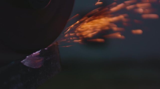 Macro: Worker cutting steel with an angle grinder in a metal workshop, bright sparks flying. Industrial tool, heat, and precision in construction and manufacturing