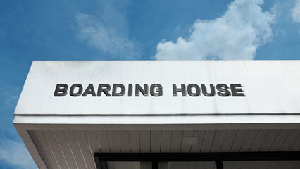 Boarding House word sign displayed on building under clear blue sky, representing accommodation, lodging, residential facilities, and hospitality services