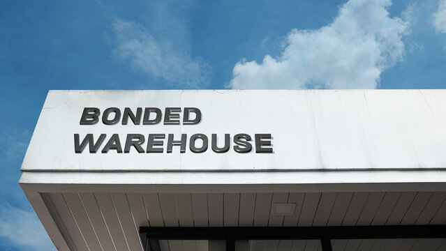 Bonded Warehouse word sign displayed on building under clear blue sky, representing storage, logistics, shipping, and secure commercial facilities