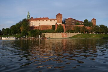 Historic Wawel Castle complex and Vistula River with beautiful reflections in foreground in afternoon sunlight. Krakow, Poland