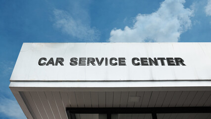 Fototapeta premium Car Service Center word sign displayed on a building under a clear blue sky, representing vehicle maintenance, repair services, automotive care, and garage facilities