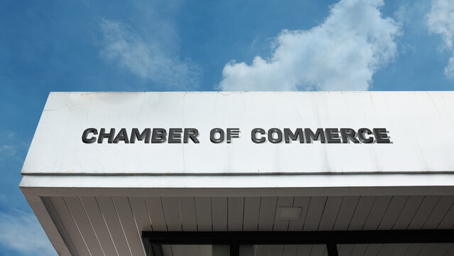Chamber of Commerce word sign displayed on a building under a clear blue sky, representing business community, trade promotion, economic development, and corporate services