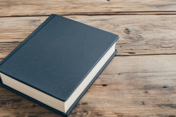 Closed hardcover book with blank cover resting on aged wooden table, offering ample copy space for text or design