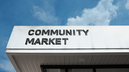 Community Market word sign displayed on a building under a clear blue sky, representing local trade, shopping, vendors, commerce, and public marketplace facilities