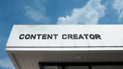 Obraz premium Content Creator word sign displayed on a building under a clear blue sky, representing digital media, creativity, social media, online production, and multimedia work