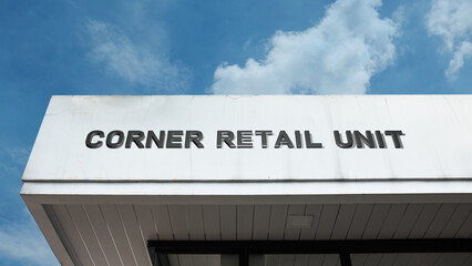 Obraz premium Corner Retail Unit word sign displayed on a building under a clear blue sky, representing shopping, commerce, small business, urban retail, and commercial facilities