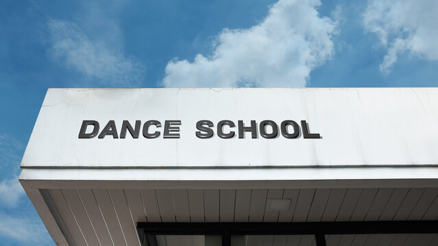 Dance School word sign on a building under a clear blue sky, representing performing arts, music, choreography, education, training, and community activities