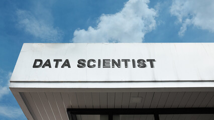 Data Scientist word sign on a building under a clear blue sky, representing technology, analytics, data, IT, computing, digital services, and business intelligence