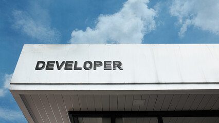 Developer word sign on a building under a clear blue sky, representing construction, real estate development, architectural services, urban planning, and professional development