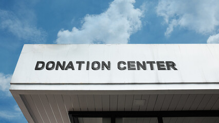 Donation Center word sign displayed on a building under a clear blue sky, representing charitable contributions, community support, and a place for giving.