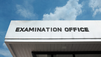 Examination Office sign displayed on a building against a clear blue sky, symbolizing academic testing, grading, certification, administrative procedures, and educational governance