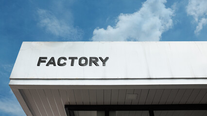 Factory sign displayed on a building against a clear blue sky, symbolizing industrial production, manufacturing, commercial output, machinery, and economic supply chain