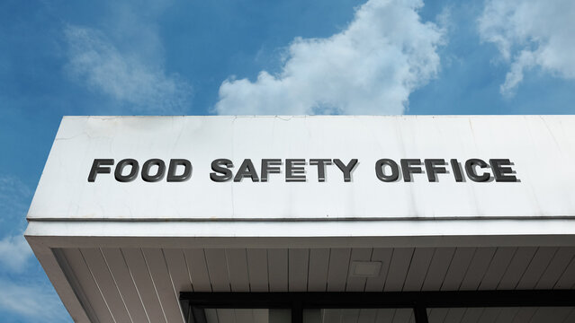 Food Safety Office word sign displayed on a modern building under a clear blue sky, representing inspection, regulation, compliance, and public health services.