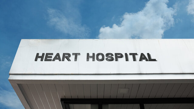 Heart Hospital sign displayed on a building against a clear blue sky, symbolizing cardiology, specialized medical care, surgery, treatment, and patient aid