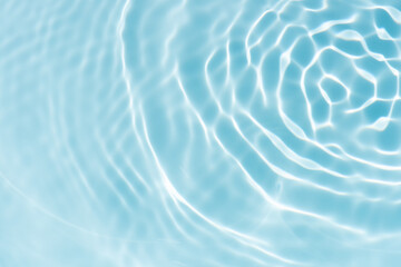 Blue water with ripples on the surface. Defocus blurred transparent blue colored clear calm water surface texture with splashes and bubbles. Water waves with shining pattern texture background.