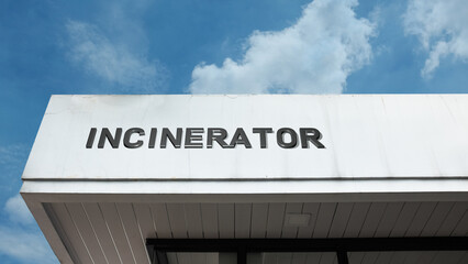 Obraz premium Incinerator sign on a building against a clear blue sky, symbolizing waste management, refuse disposal, energy conversion, industrial facility, and heat