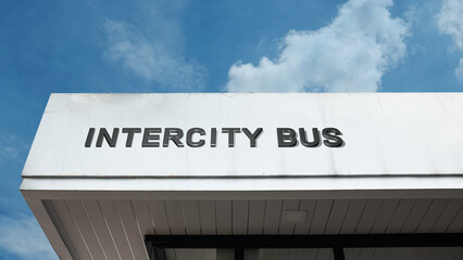 Obraz premium Intercity Bus sign on a building against a clear blue sky, symbolizing public transport, long-distance travel, terminal, road connectivity, and station