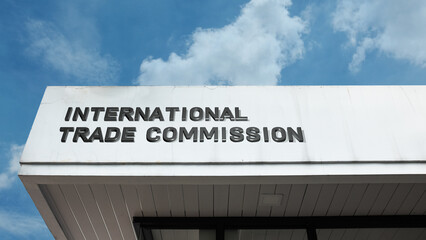 Naklejka premium International Trade Commission sign on a building against a clear blue sky, symbolizing global commerce, economic policy, trade regulation, governmental oversight, and body