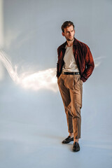 A portrait of a man relaxing on a wooden chair, wearing earthy tones that complement the soft interior lighting. His calm expression creates a warm lifestyle and editorial mood.