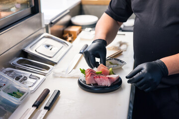Skilled Japanese chef preparing raw fish sashimi carefully