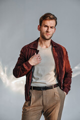 A close portrait of a man in a suede jacket looking slightly aside with calm confidence. Soft lighting adds depth and highlights the warm tones of his outfit, creating a polished fashion look.