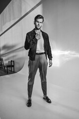 A dynamic monochrome image of a man walking with confident posture, dressed in a minimal casual outfit. Light streaks add motion and atmosphere, giving the scene a modern editorial vibe.