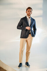 A man lounges on the staircase in a stylish blazer and trousers, creating a relaxed yet fashionable editorial composition.