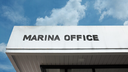 Obraz premium Marina Office sign on a building against a clear blue sky, symbolizing harbor administration, recreational boating, nautical management, dockyard service, and coast