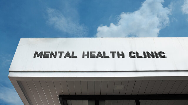 Mental Health Clinic sign on a building against a clear blue sky, symbolizing psychiatric care, therapeutic services, emotional support, counseling, and wellness
