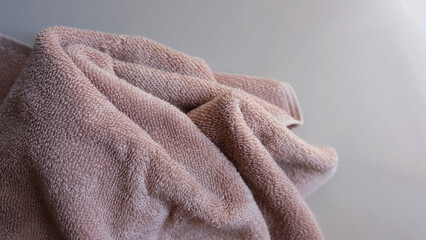 Brown bath towel on a white textured background. 