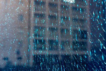Blue shattered glass reflecting apartment windows, with cracks suggesting violence, danger, and...