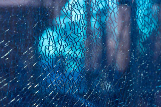 Blue shattered glass completely covered with cracks, creating a fragmented, textured surface with sharp patterns and a dramatic visual effect