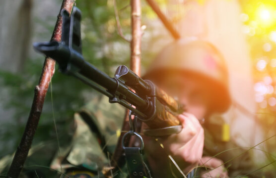 Soldier aiming rifle in dense forest during military training exercise at sunset
