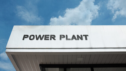 Obraz premium Power Plant word signage on a massive industrial building under a blue sky, symbolizing energy generation, electricity, industrial infrastructure, and utility supply