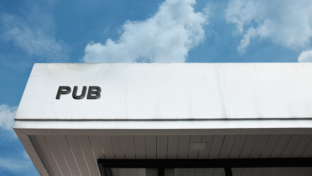 Pub word signage on a commercial building under a blue sky, symbolizing a public house, bar, beer, social gathering, entertainment, and nightlife establishment