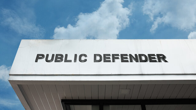 Public Defender word signage on a government or legal building under a blue sky, symbolizing legal representation, indigent defense, justice, law, and civil rights advocacy