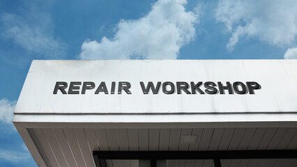 Obraz premium Repair Workshop word signage on an industrial or technical building under a blue sky, symbolizing professional maintenance, fabrication, specialized service, technical expertise, and fixing