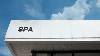 Spa word signage on a commercial relaxation or wellness building under a blue sky, symbolizing beauty treatment, health, hydrotherapy, massage, rejuvenation, therapy, and luxury retreat