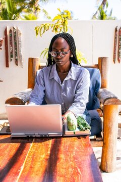 A beautiful young African woman working remotely on her laptop outdoors