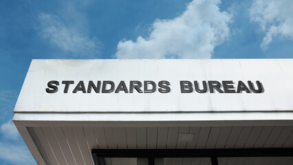 Obraz premium Standards Bureau word signage on a government or regulatory building under a blue sky, symbolizing quality control, official regulation, measurement, certification, research, consistency, and metrolog