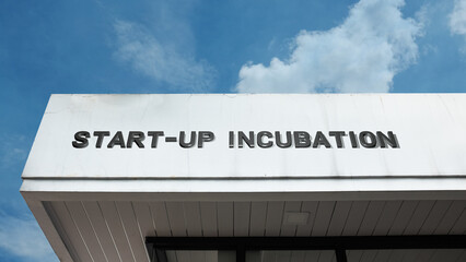 Start-up Incubation word signage on a commercial or institutional building under a blue sky, symbolizing business innovation, new companies, entrepreneurship, mentorship, technology, and economic grow